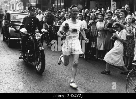 Flamme olympique sur le dernier circuit à Wembley - dans les premières heures de ce matin Bicknell, un des porteurs de la flamme arrive à Redhill, Surrey, portant la torche olympique. Des foules enthousiastes tard dans la nuit dernière tôt ce matin ont vu des coureurs porter la flamme olympique à travers les villes du sud de l'Angleterre et le long des routes de campagne sur le dernier tour de son voyage de 2000 miles de l'Olympe à Wembley. 29 juillet 1948. Banque D'Images