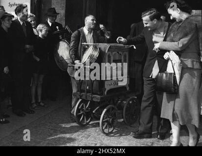 Nous, musiciens, devons nous tenir ensemble - Yehudi Menuhin, violoniste de renommée mondiale, récompense un joueur d'orgue Barrel de Berlin avec un gros conseil pour sa sérénade alors que l'ancien quitte le théâtre du Titania Palace après une répétition avec l'Orchestre Philharmonique de Berlin, septembre 21. Menuhin est arrivé à Berlin le 19 septembre pour une tournée de concerts. À droite, Mme Menuhin. 23 septembre 1949. (Photo par photo de presse associée). Banque D'Images