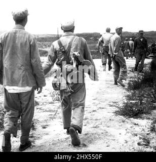 Soldat chargé -- deux soldats communistes chinois, l'un chargé d'équipement comprenant une mitrailleuse, s'éloignent d'un photographe de l'ONU dont le convoi à Kaesong a été stoppé vendredi par les hautes eaux. Les ingénieurs alliés ont travaillé à réparer les dégâts causés par les inondations afin que les convoi de cessez-le-feu puissent passer demain, alors que les communistes devraient donner leur réponse à l'ordre du jour de l'armistice. 24 juillet 1951. (Photo par AP Wirephoto). Banque D'Images