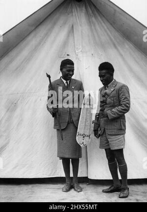 Ils ont hésité dans la frise froide de Melbourne, mais la pluie ne pouvait pas étouffer leurs esprits, William Otimaekera (à droite) et Rovert Salau, des îles Salomon, ont souri joyeusement alors qu'ils ont exposé leurs îles curieuses aujourd'hui. Ils sont ici pour assister au camp adventiste du septième jour au parc royal. 23 janvier 1939. Banque D'Images