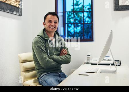 Les choses sont bonnes pour ma mise en route. Photo d'un homme assis derrière son ordinateur dans son bureau. Banque D'Images
