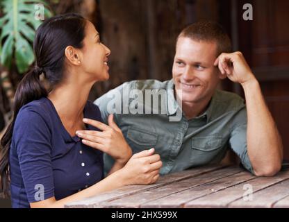 Homme, j'aime rattraper tous les potins féminins. Un jeune couple discutant dans un café. Banque D'Images