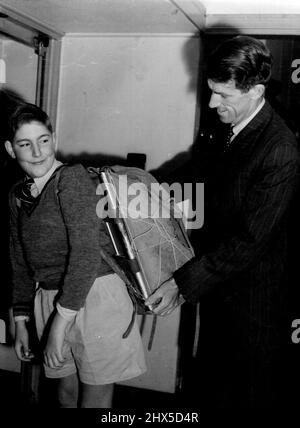 Anthony Malcolm, 12 ans, fils de M. J. Malcolm, délégué commercial principal de la Nouvelle-Zélande à Sydney, porte Mt. L'Everest conquérant le pack de Sir Edmund Hillary à la salle des douanes de la base de bateau de Rose Bay ce matin, lorsque Sir Edmund a quitté Teal pour Auckland. M. Malcolm et Anthony ont vu Sir Edmund. 8 août 1953. Banque D'Images