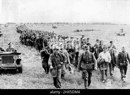 Les Allemands de falaise marchent jusqu'au camp de détention : cette longue ligne de prisonniers allemands, capturés par les troupes britanniques et canadiennes dans le poutrelle de falaise du nord de la France, est emmenée le long d'un camp de prisonniers de guerre sous l'escorte de troopeurs PEP-Riding. 28 août 1944. (Photo par photo de presse associée). Banque D'Images