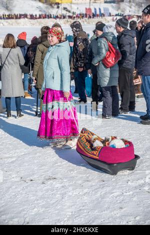 Femme Komi avec un enfant sur un traîneau en plastique au Festival des éleveurs de rennes à Salekhard, Yamalo-Nenets Autonomous Okrug, Russie Banque D'Images