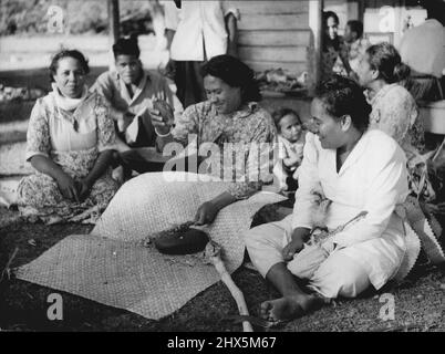 La Reine visitera les Tonga -- la femme tongan qui fait du Kava. La boisson nationale, faite à partir des racines séchées de plantes appartenant à la famille du poivre. À Tonga, c'est la femme qui prépare la boisson, contrairement aux Fidji où les hommes sont responsables. La section de la racine est martelée entre deux pierres de basalte. Les fragments qui tombent sur le tapis s'étendent en dessous. Ils sont rassemblés ensemble l'aide placée le bol en bois, visible sous le bras de la fille. H.M. la Reine et le duc d'Édimbourg arrivent à Tonga le 19 décembre. Leur deuxième arrêt du pacifique. 2 décembre 1953. (Photo de Paul Popper). Banque D'Images