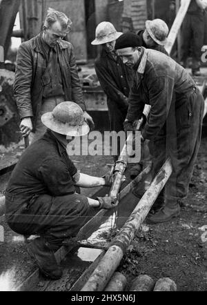 Champ pétrolier secret de Grande-Bretagne -- sortir le noyau du plus profond tunnel jamais fait dans ce pays - 7 400 pieds. Le rocher vu sortir est assez chaud. Un champ pétrolier britannique, dont l'emplacement doit encore être gardé secret, produit du pétrole au rythme de 100 000 tonnes par an. Les experts qui ont foré pour le pétrole en Perse sont parmi les 1 000 travailleurs de ce village autrefois calme. L'huile est pompée à la surface par de petites pompes électriques sans bruit qui ne prennent que quelques mètres carrés d'espace, et sont camouflés pour s'adapter à la campagne environnante. 16 janvier 1945. (Photo de London News Agency photos). Banque D'Images