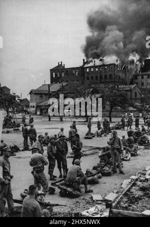 Marines à Inchon -- les troupes de la Division Marine américaine 1st fument bavardent et se détendent pendant qu'elles attendent des ordres pour aller de l'avant dans la route des Nations Unies vers Séoul, ancienne capitale de la Corée du Sud, tenue par l'ennemi. Les Marines sont montrées ici à Inchon, port de la côte ouest à partir duquel le trajet de Séoul a été lancé. En arrière-plan est un entrepôt de tabac en feu. (16 septembre 1950. Photo reçue par air aujourd'hui). 25 septembre 1950. (Photo de Reuterphoto). Banque D'Images