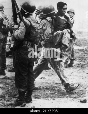 Pow blessé transporté à la station de premiers secours -- Un prisonnier de guerre communiste blessé est transporté dans les bras d'un parachutiste américain vers une station de premiers secours pendant les combats sanglants de la zone 76 sur l'île de Koje. D'autres parachutistes, certains portant des masques à gaz, se tiennent à l'entrée de l'enceinte de Pow. 10 juin 1952. (Photo par AP Wirephoto). Banque D'Images