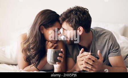 Café et temps de qualité, perfection. Photo d'un jeune couple heureux ayant un café ensemble dans le lit à la maison. Banque D'Images