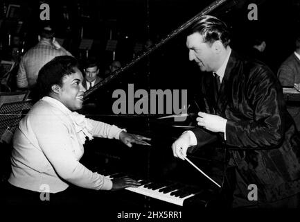 « La reine du clavier » réalise l'ambition de sa vie -- Stanford Robinson, chef d'orchestre de l'orchestre philharmonique de Londres, vu parler de technicités avec Winfred Atwell, lors d'une répétition du concert de dimanche. Lorsqu'un artiste de la variété d'étoiles a obtenu une réservation Palladium, une performance de commande royale, une vente de disque de plus de 5 millions, plus d'un an de résidence dans un West End Theatre et est le propriétaire d'une grande maison, une voiture magnifique, des bijoux de fure, etc., On imagine que toutes les ambitions ont été satisfaites, mais ce n'est pas le cas de Winfred aswell. 27 novembre 1954. (Photo de Fox Banque D'Images