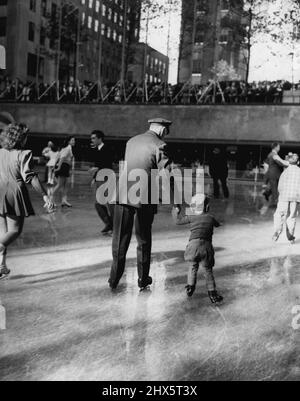 Centre Sports Oasis -- l'un des préposés à la patinoire du Rockefeller Center aide un jeune amateur de sports sur la glace. Dans une enceinte encastrée au milieu de « radio City », les unités de congélation de la patinoire sont fréquemment utilisées pour refaire surface de la patinoire. À ces moments, les hommes patinant derrière de larges pelles à neige, toilettage de la glace, sont les principales attractions. 10 novembre 1946. (Photo par Wide World photos). Banque D'Images