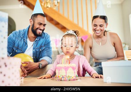 Faire un vœu est la meilleure partie. Photo d'une petite fille célébrant un anniversaire avec ses parents à la maison. Banque D'Images