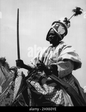 Épée indemne, ce guerrier tribal dans un magnifique manteau et avec un casque forgé en acier, s'assied à l'attention sur son mont comme il salue la Reine à l'hier (2-2-56) Durbar à Kaduna. Près de 7 000 Northern ian tribesman ont participé au rassemblement qui a été observé par 80 000 personnes. 17 février 1955. (Photo de Daily Mirror).;Sword sorti de sa peau, ce guerrier tribal dans un magnifique manteau et avec un casque en acier forgé, est assis à l'attention sur son support alors qu'il salue la Reine à l'hier Banque D'Images