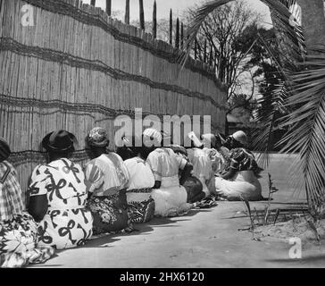 Barotse femmes -- face à la palisade de la cour intérieure les femmes de la maison s'assoient et chantent leur chanson traditionnelle de bienvenue au chef Paramount à son retour d'un long voyage. Une ou deux des femmes portent un type plus moderne de robe, mais la majorité préfèrent toujours l'agitation victorienne. Les femmes plus âgées ont conservé soigneusement leurs robes pendant de nombreuses années. 23 juin 1952. (Photo de Nigel Watt, Camera Press).;Barotse Women -- face à la palissade de la cour intérieure Banque D'Images