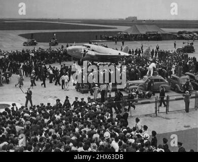 Hughes' Ship vient dans des acclamations, des flashs, des cliqueurs caméras et un bataillon de New York's huskiles flics ont accueilli cinq aviateurs fatigués qui ont visité le monde en sept sauts en moins de quatre jours à l'aéroport Floyd Bennett, juillet 14. Voici l'avion au milieu d'une foule sélectionnée alors que l'arrière de la clôture et un cordon de policiers est un coin de la foule à portée de main à la fin du vol Hughes. 14 juillet 1938. (Photo par photo de presse associée). Banque D'Images