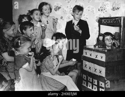 Pas d'adultes - à moins d'être accompagné par des enfants -- Un petit garçon divertit ses camarades de jeu avec des marionnettes à gants dans l'appartement des enfants. Dans un bloc de tenement enfumé dans le quartier de Bermondsey à Londres est un appartement pour enfants de trois pièces où les garçons et les filles peuvent faire exactement comme ils le souhaitent et tous les adultes sont interdits - sauf s'ils sont accompagnés d'un enfant. L'appartement a été fourni par des travailleurs sociaux. Un gardien et son personnel bénévole sont toujours à votre disposition si les enfants veulent de l'aide, mais ils n'interfèrent jamais et n'essaient jamais d'organiser le Banque D'Images