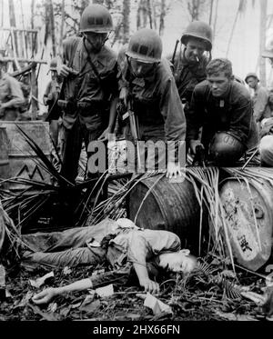 Un Japonais mort se trouve parmi les équipements ennemis avisés tandis que les troupes américaines se déplacent le long de la plage lors de l'attaque sur Hollandia, détenu par le Japon, en Nouvelle-Guinée hollandaise. 25 avril 1944. (Photo par image du Département de l'information). Banque D'Images