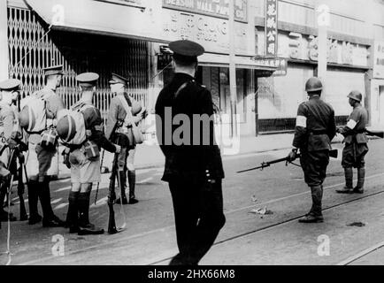 Le silence suit un incident dramatique. Un officier britannique des Welch Fusiliers arrête ses hommes sur la route de Nanking peu après qu'un étudiant chinois ait lancé une grenade dans une colonne de troupes lors de la « marche de la victoire » japonaise à travers Shanghai. L'étudiant a été tué dans le pandemonium qui a suivi. Notez les entrées japonaises sur la droite avec leurs baïonnettes fixes. 7 janvier 1938. Banque D'Images