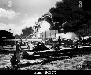 Dans un contexte de fumée et de flammes, la base aérienne navale à épave est montrée après l'une des attaques de fuite par le bombardier Jap sur Pearl Harbor, le 7th décembre 1941. Note aile de bombardier de patrouille blaqué, (premier plan) énorme boule de flamme (arrière-plan) est venu de l'explosion qui s'est produite juste comme cette photo a été prise. Picture vient d'être publié par le département de la Marine à Washington. 4 février 1943. Banque D'Images