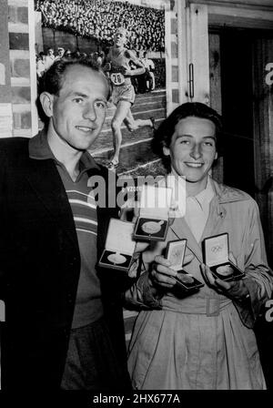 Le Zatopeks gagnant -- Emil Zatopek de Tchécoslovaquie, vainqueur des Jeux Olympiques de 5 000 mètres, 10 000 mètres et marathon, avec son épouse Dana Zatopekova, qui a gagné le javelin féminin, montrent leurs quatre médailles d'or à l'Otaniemi ***** . En arrière-plan est une photo d'action olympique de Zatopek. 31 juillet 1952. Banque D'Images