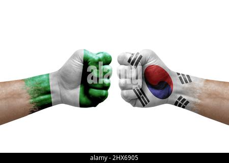 Deux mains poinçonner l'une à l'autre sur fond blanc. Les drapeaux de pays ont peint les poings, le concept de crise de conflit entre le nigeria et la corée du Sud Banque D'Images
