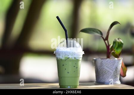Gros plan d'une tasse en plastique de thé vert glacé ou de Matcha dans une tasse en plastique prête à boire, posez-la sur une table en bois. Banque D'Images