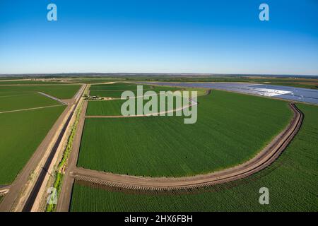 Vue aérienne des champs de culture circulaires verts avec système d'irrigation et panneau solaire adjacent Banque D'Images