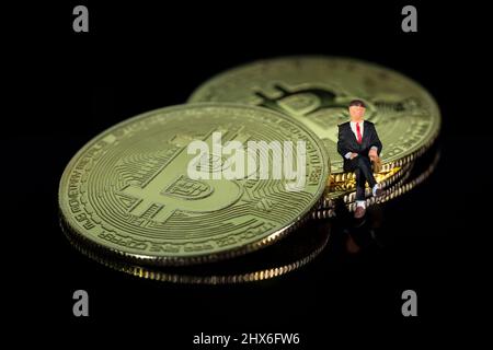 Petit homme d'affaires assis sur Bitcoin pièces de futur concept d'investissement Banque D'Images