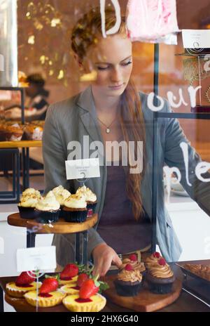 Servir uniquement les plus frais à ses clients. Photo d'une jeune femme attrayante travaillant dans une boulangerie. Banque D'Images