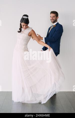 La première danse, mais pas la dernière. Photo studio d'un jeune couple récemment marié debout sur fond gris. Banque D'Images