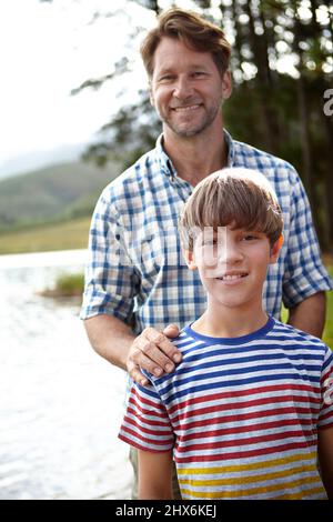 Si fier de mon fils. Portrait d'un fier père et de son fils debout à côté d'un lac. Banque D'Images