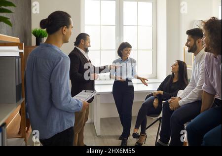 Les employés communiquent entre eux en racontant des histoires et en discutant de leur travail pendant la pause. Banque D'Images