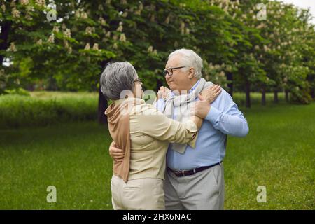 Un homme et une femme heureux, âgés et amoureux, dansant la valse dans un magnifique parc d'été vert Banque D'Images