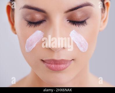 La peau douce est un soin constant. Photo d'une belle jeune femme posant sur un fond gris. Banque D'Images