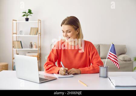 Jeune femme heureuse à la maison apprenant l'anglais assistant à des cours en ligne à l'aide d'un ordinateur portable. Banque D'Images