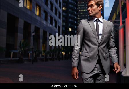 En ville. Photo d'un beau homme d'affaires en costume qui marche dans la ville la nuit. Banque D'Images