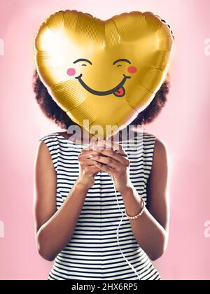 Un peu stupide. Photo courte d'une jeune femme tenant un ballon en forme de cœur. Banque D'Images