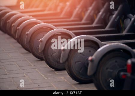 Set Electric scooters sont dans le parking prêt pour la location, lumière du soleil. Banque D'Images