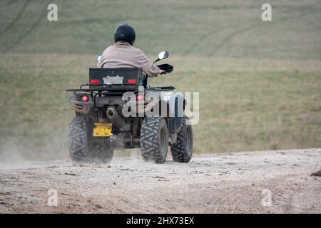 un quad avec des lumières sur la conduite de son quad hors-route le long d'une piste de pierre campagne ouverte Banque D'Images