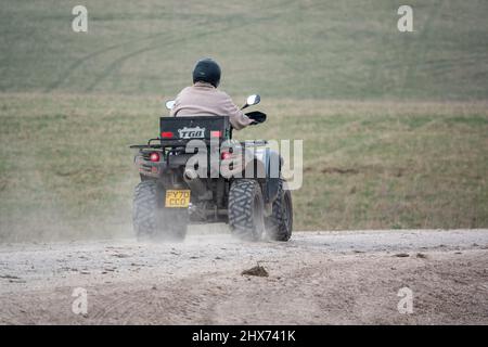 un quad avec des lumières sur la conduite de son quad hors-route le long d'une piste de pierre campagne ouverte Banque D'Images