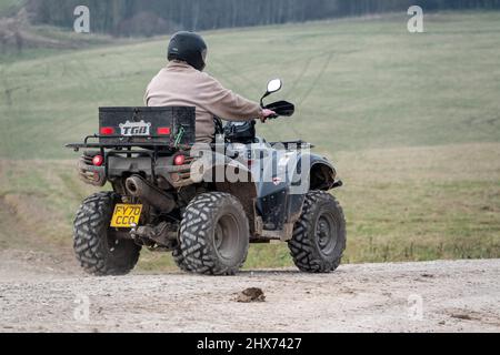 un quad avec des lumières sur la conduite de son quad hors-route le long d'une piste de pierre campagne ouverte Banque D'Images