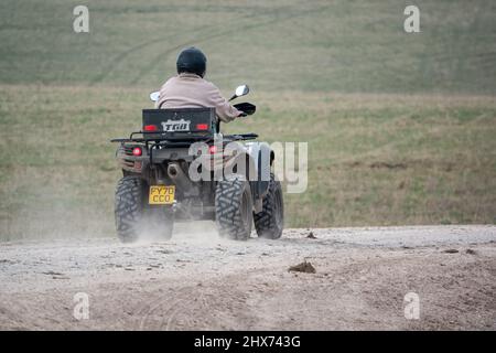 un quad avec des lumières sur la conduite de son quad hors-route le long d'une piste de pierre campagne ouverte Banque D'Images