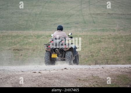 un quad avec des lumières sur la conduite de son quad hors-route le long d'une piste de pierre campagne ouverte Banque D'Images