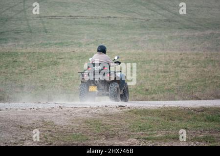 un quad avec des lumières sur la conduite de son quad hors-route le long d'une piste de pierre campagne ouverte Banque D'Images