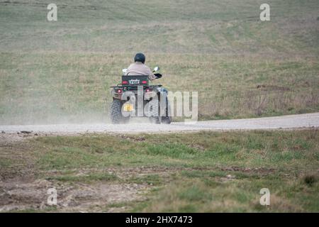 un quad avec des lumières sur la conduite de son quad hors-route le long d'une piste de pierre campagne ouverte Banque D'Images