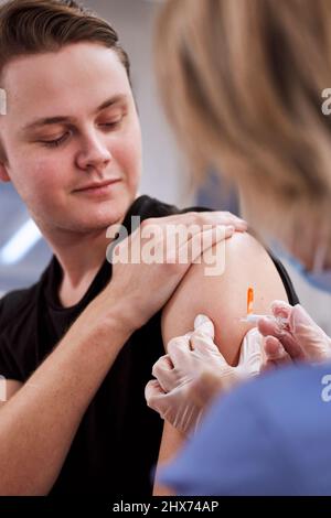 Jeune homme se vaccine contre Covid-19 Banque D'Images