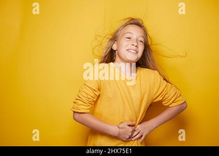 Une petite fille qui exprime divers sentiments sur son visage et des gestes qu'elle fait ressortir à travers son corps et son sublime sourire qui fournit de l'énergie. Banque D'Images