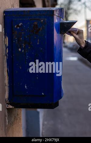 la main d'une femme met un emballage fin dans la boîte aux lettres. Photo de haute qualité Banque D'Images