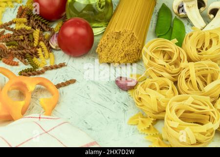 Divers types de pâtes sur la table. Divers types de pâtes et de nouilles crues avec légumes. Concept culinaire de la cuisine italienne. Collection Banque D'Images